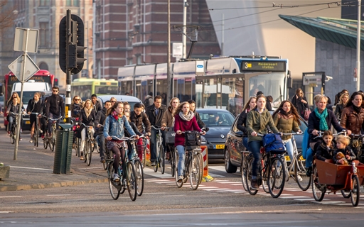 Een fiets, tram en bus op een drukke weg in de Vervoerregio Amsterdam