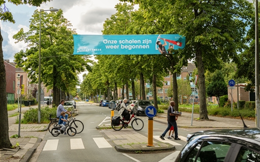 Foto van straat met fietsers en spandoek met 'Scholen zijn weer begonnen'