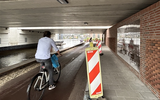 Foto van een fietser die de fietstunnel onder Brug Ouderkerk in fietst aan de Ouder Amstel zijde